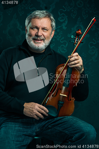 Image of Senior musician playing a violin with wand on black background