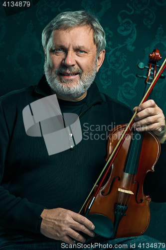 Image of Senior musician playing a violin with wand on black background