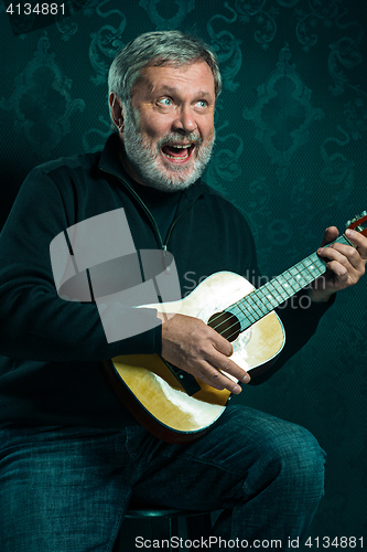 Image of Studio portrait of senior man with guitar.