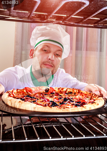 Image of Chef cooking pizza in the oven.