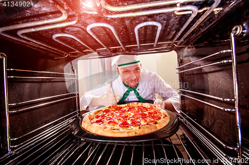 Image of Chef cooking pizza in the oven.