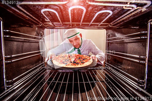 Image of Chef cooking pizza in the oven.