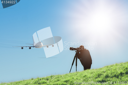 Image of Silhouette of spotter photographer capturing photos of landing airplane