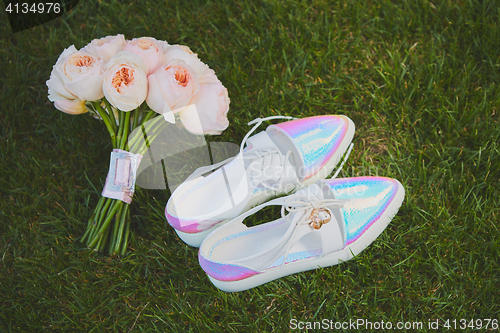 Image of wedding bouquet and shoes lying down on green grass
