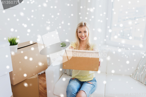 Image of smiling young woman with cardboard box at home
