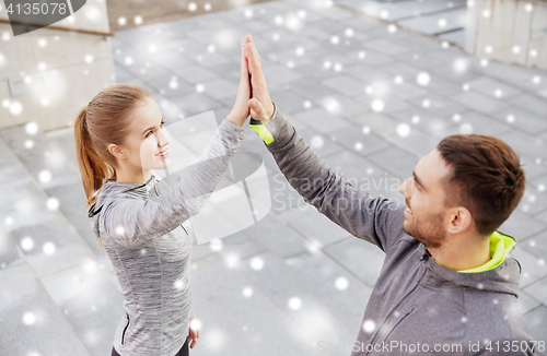 Image of couple of sportsmen making high five outdoors