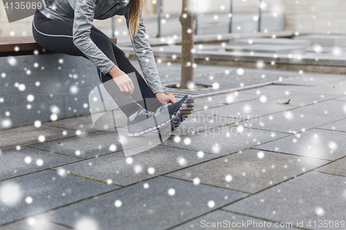 Image of close up of sporty woman tying shoes outdoors