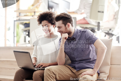 Image of happy creative team with laptop in office