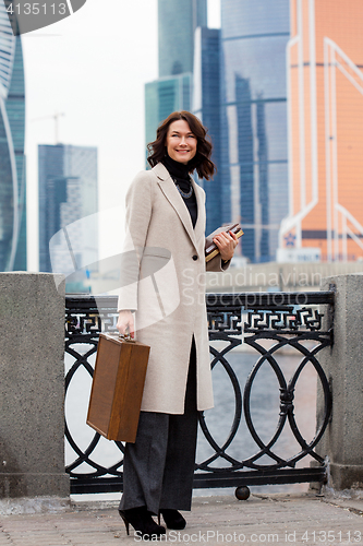 Image of brunette with a wooden case and books in her hands