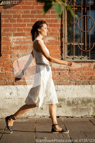 Image of beautiful woman in a white dress goes on old street