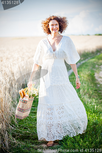 Image of Pretty smiling Woman Outdoors with wicker bag with natural meal 