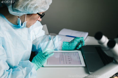 Image of Side view of scientist working on tablet