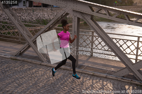 Image of african american woman running across the bridge