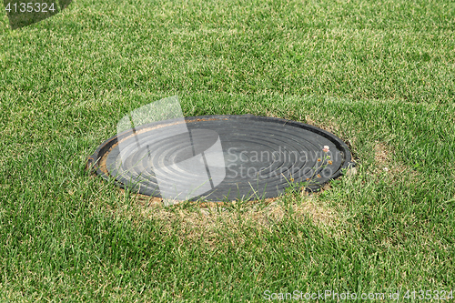 Image of Metal manhole in a background of green grass on the field