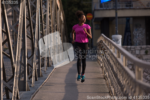 Image of african american woman running across the bridge