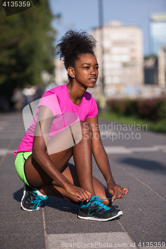 Image of African american woman runner tightening shoe lace