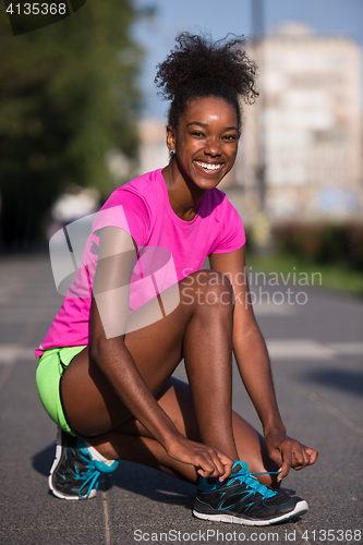 Image of African american woman runner tightening shoe lace