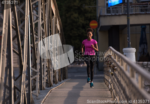 Image of african american woman running across the bridge