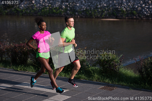 Image of young smiling multiethnic couple jogging in the city