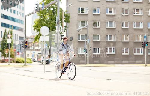 Image of young hipster man with bag riding fixed gear bike