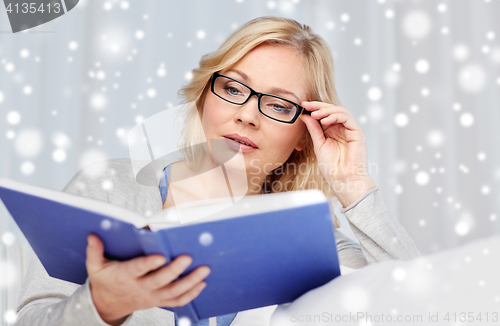 Image of woman reading book and sitting on couch