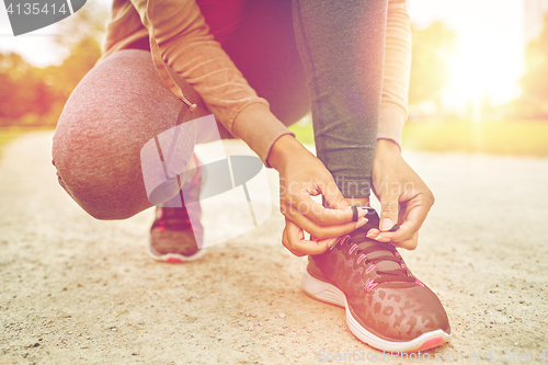 Image of close up of woman tying shoelaces outdoors