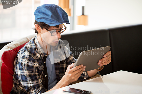 Image of man with tablet pc sitting at cafe table