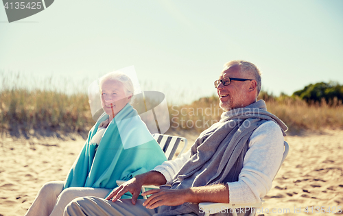 Image of happy senior couple in chairs on summer beach