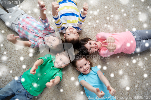 Image of happy kids lying on floor and showing thumbs up
