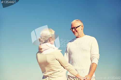 Image of happy senior couple holding hands outdoors