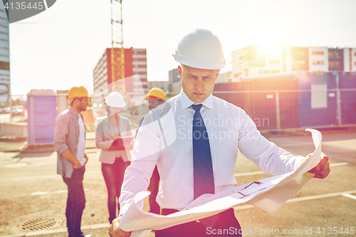 Image of architect with blueprint on construction site