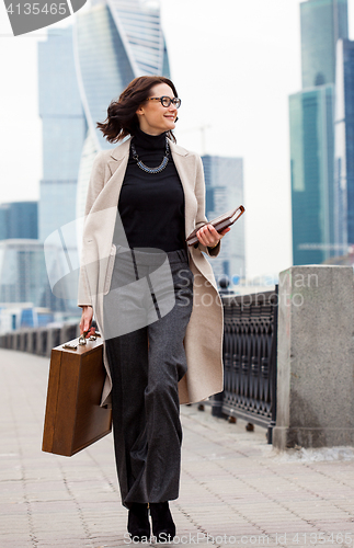 Image of beautiful smiling middle-aged woman in a bright coat goes with a