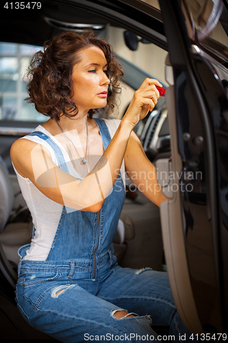 Image of mechanic woman in a blue overalls repair with a screwdriver the 