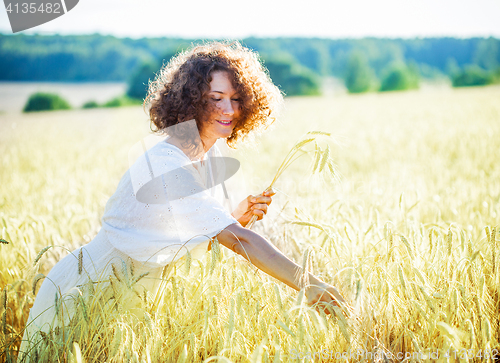 Image of smiling woman in a light dress collects in the ears of the field