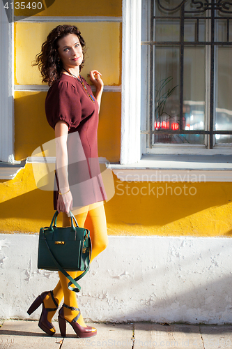 Image of smiling middle-aged woman in a burgundy dress and handbag