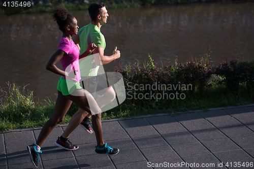 Image of young smiling multiethnic couple jogging in the city