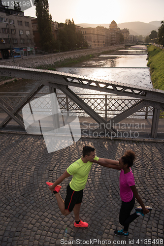 Image of jogging couple warming up and stretching in the city