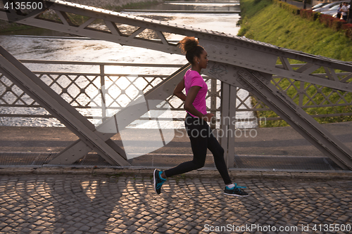 Image of african american woman running across the bridge