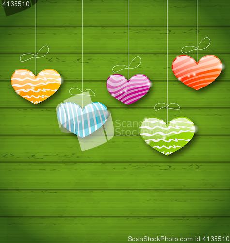 Image of Colorful hearts hanging on green wooden texture for Valentine Da