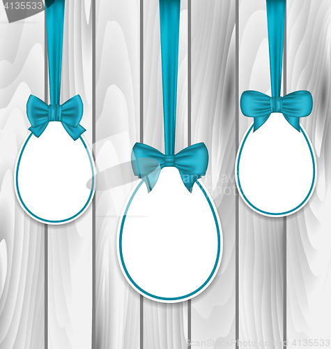 Image of Easter paper eggs wrapping blue bows on wooden grey background