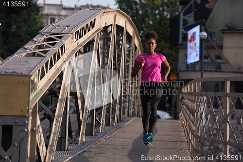 Image of african american woman running across the bridge