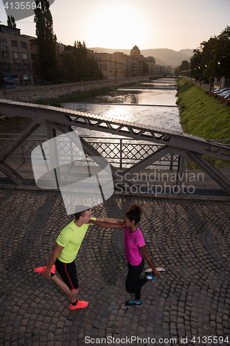 Image of jogging couple warming up and stretching in the city