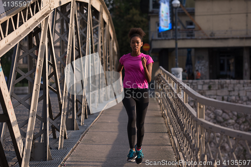 Image of african american woman running across the bridge