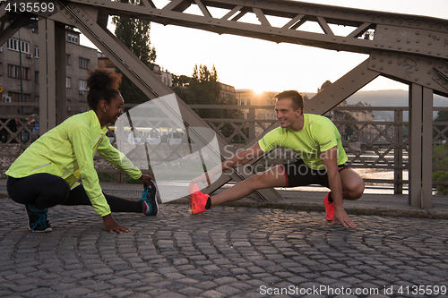 Image of jogging couple warming up and stretching in the city