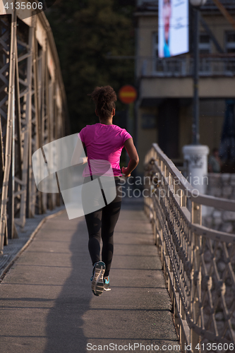 Image of african american woman running across the bridge