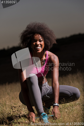 Image of black woman runner tightening shoe lace