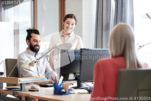 Image of happy creative team with computers in office