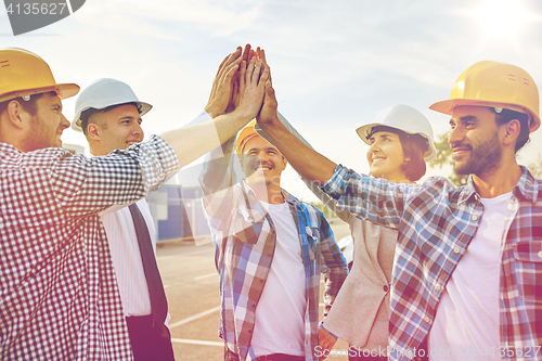 Image of close up of builders in hardhats making high five