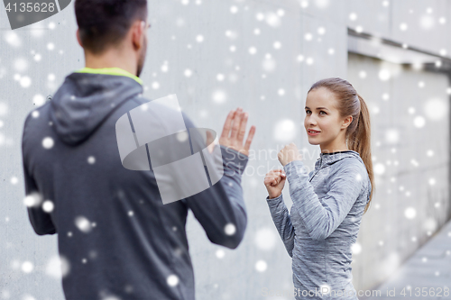 Image of happy woman with coach working out strike outdoors