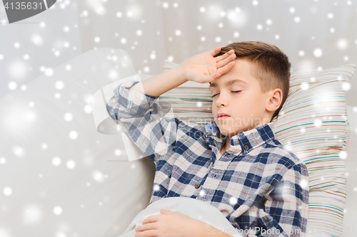 Image of ill boy lying in bed and suffering from headache